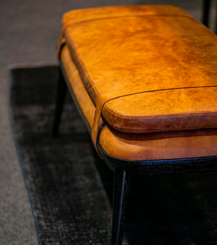 Close-up of a brown leather bench with a blurred background